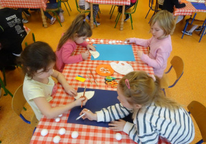 Dzieci naklejają papierowe talerzyki na papier.